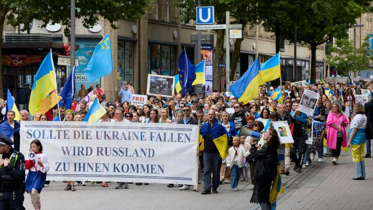 In Hamburg zieht ein Demonstrationszug mit ukrainischen Flaggen durch eine Straße.