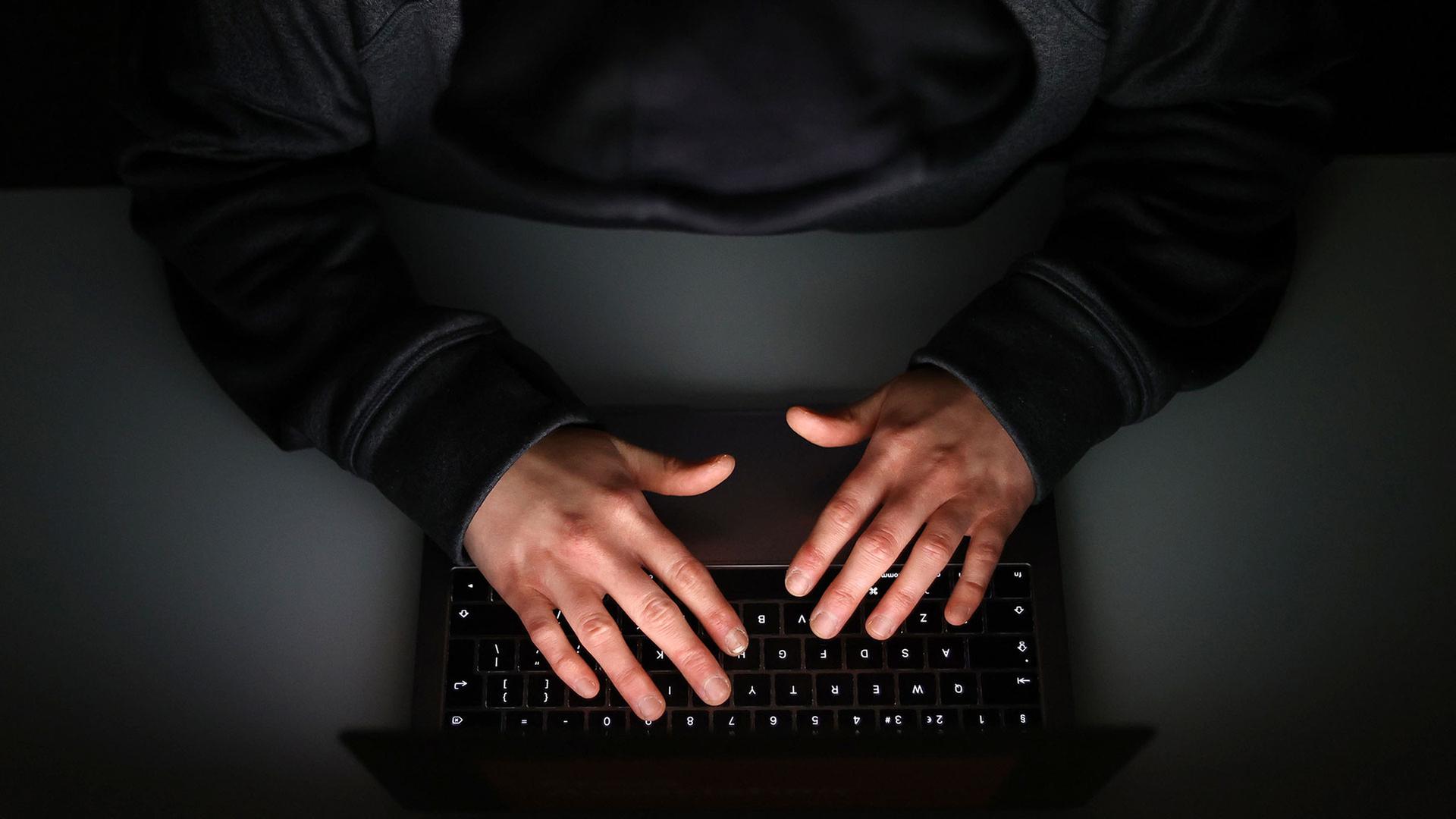 Hände tippen auf eine beleuchteten Tastatur. | picture alliance / empics