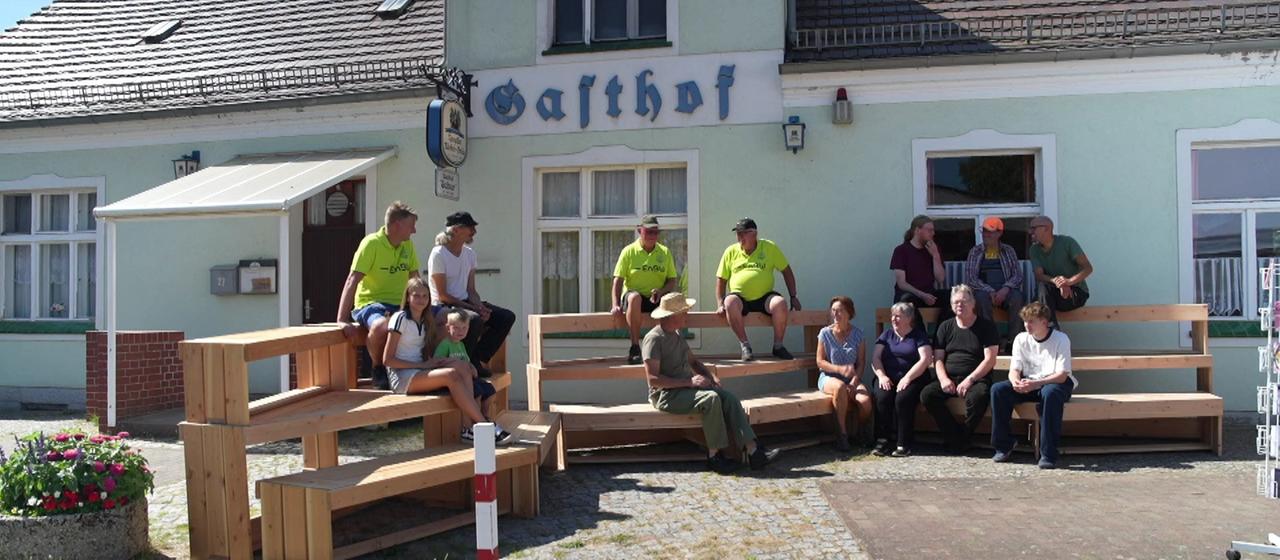 Dorfbewohner von Leißnitz sitzen vor dem "Gasthof Schur".