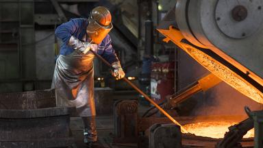 Ein Arbeiter steht an einem Schmelzofen.