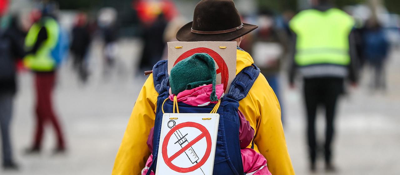 Eine Teilnehmerin einer Protestkundgebung der Initiative "Querdenker" trägt auf dem Cannstatter Wasen ein Schild gegen Impfungen auf ihrem Rücken.