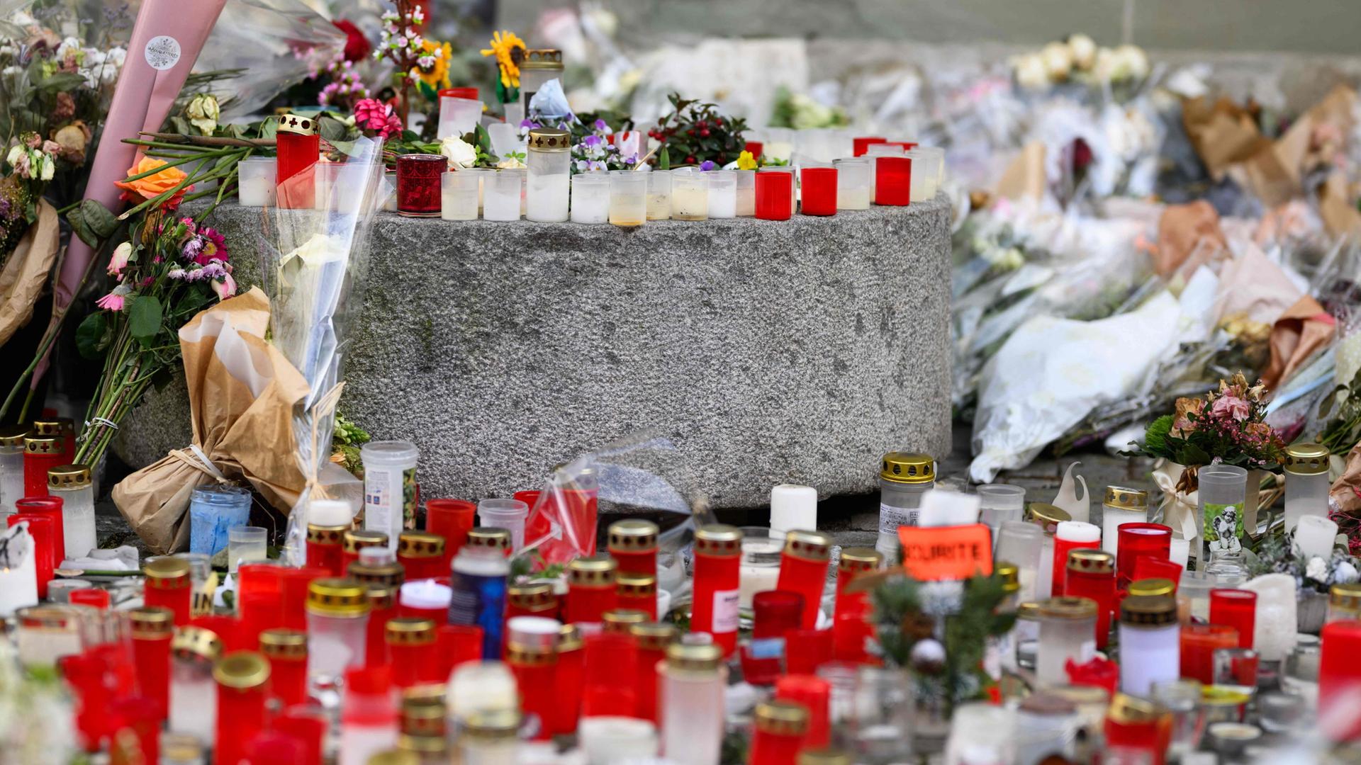 Kerzen stehen auf dem Gehweg in Gedenken an die Opfer der Brandkatstrophe vonCrans Montana an Neujahr 2026 | AFP