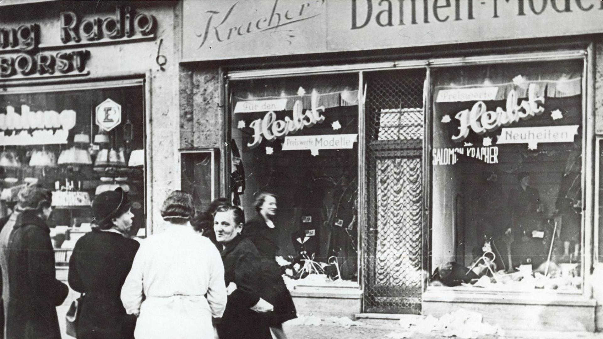 Passanten stehen im November 1938 in einer Stadt in Deutschland vor einem jüdischen Geschäft, dessen Schaufensterscheiben am 9.11.1938 zerstört wurden. | picture alliance/AP Images