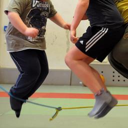 Übergewichtige Kinder machen Sport in einer Turnhalle.