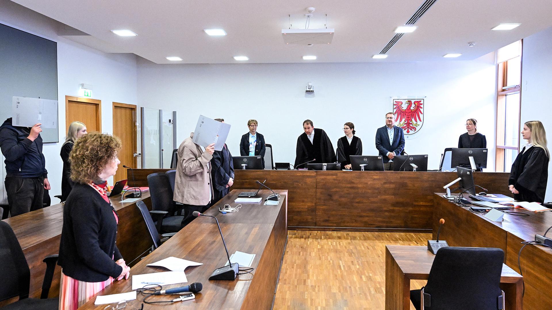 Die beiden Angeklagten im Potsdamer Landgericht halten sich graue Hefter vors Gesicht. (Quelle: picture alliance/dpa/Soeren Stache) | picture alliance/dpa/Soeren Stache