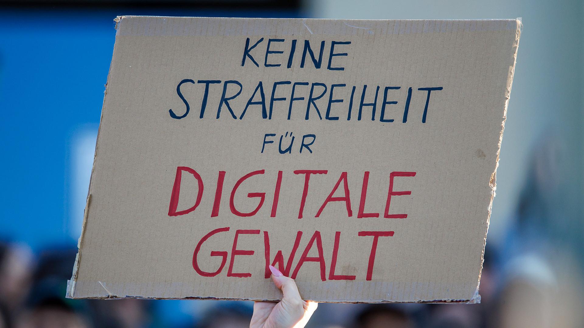 Bei einer Demonstration wird ein Pappschild mit der Aufschrift 