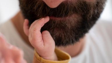 Ein Kind fasst seinem Vater in den Bart.