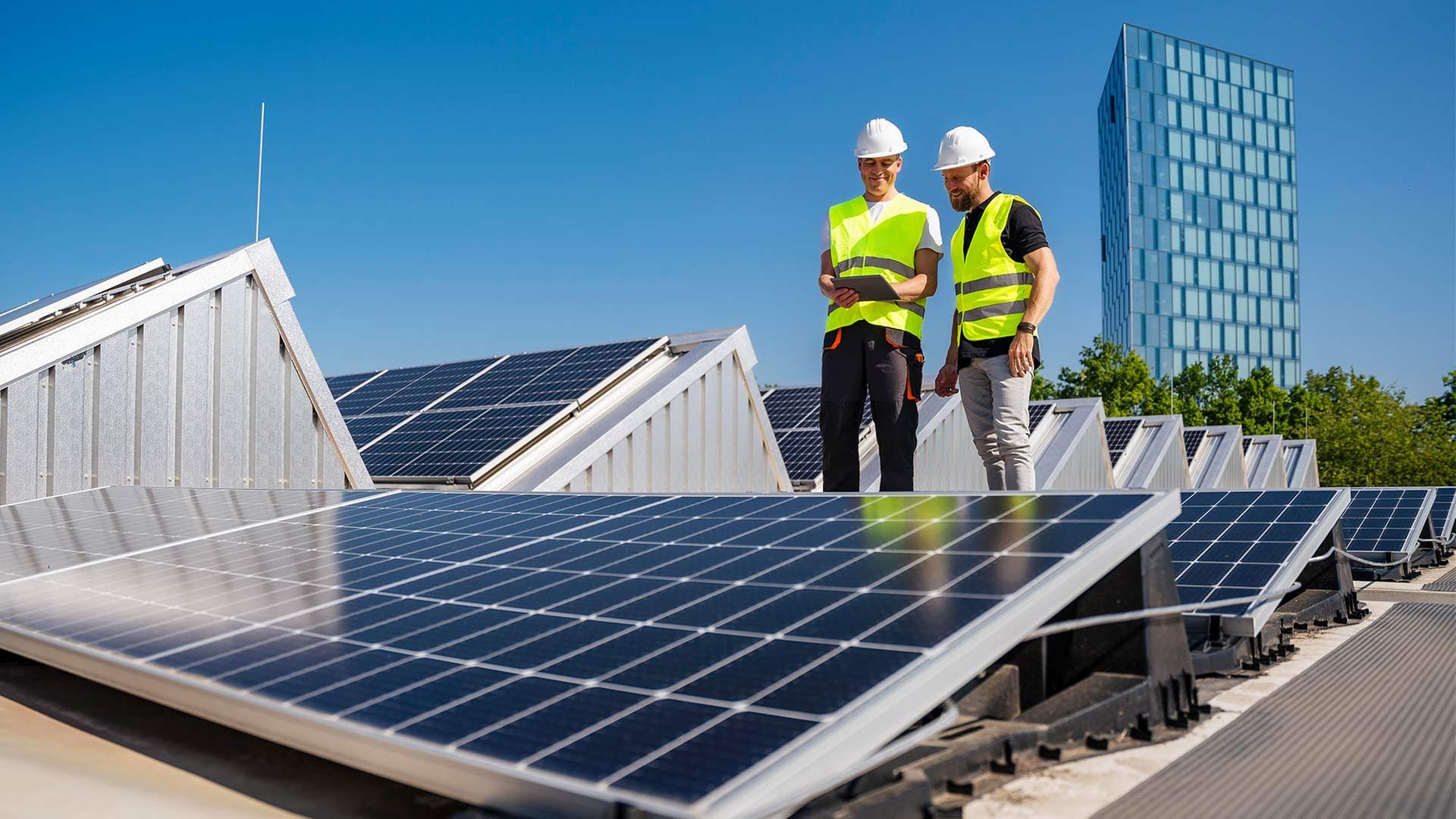 Techniker stehen bei einer Solaranlage auf einem Firmendach. | picture alliance / Westend61
