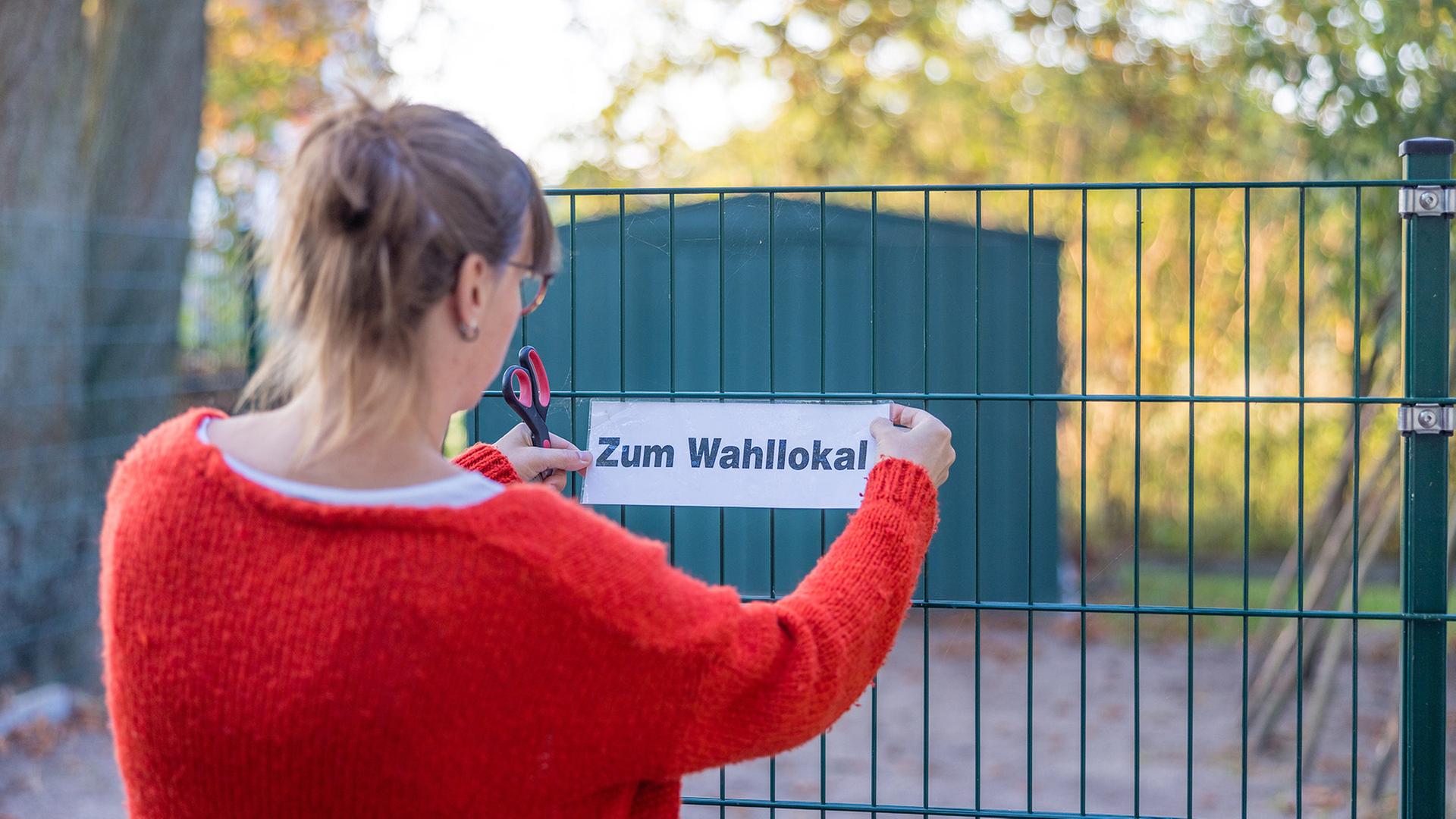 22.09.2024, Brandenburg, Potsdam: Eine Wahlhelferin bringt ein Hinweisschild vor dem Wahllokal an (Quelle: dpa/Frank Hammerschmidt)