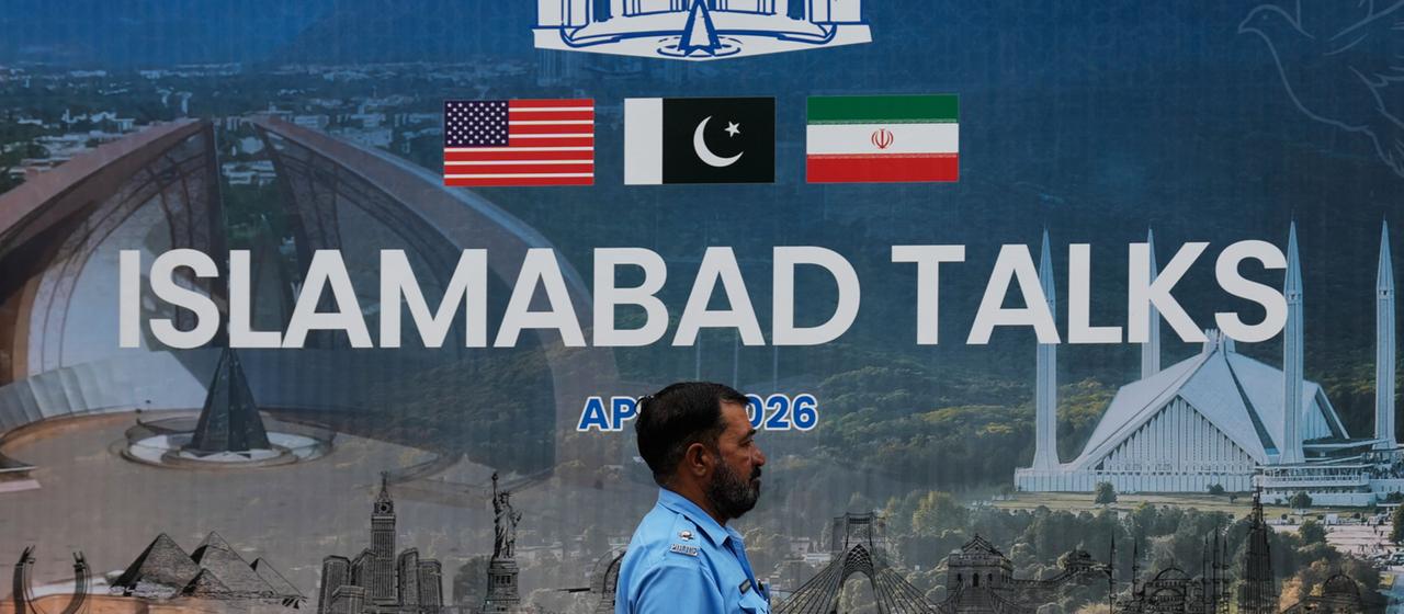 Ein Polizist vor einer Plakatwand zu den Verhandlungen zwischen den USA und dem Iran.