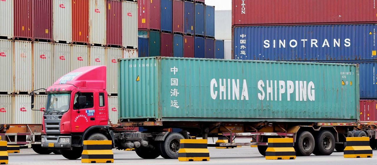 LKW mit Containern im Hafen von Qingdao, China.