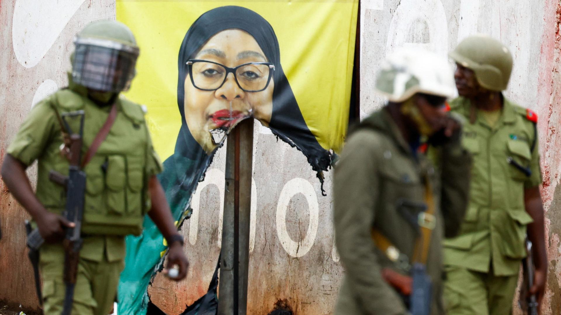 Soldaten während der Proteste in Tansania vor einem Wahlplakat von Präsidentin Samia Suluhu Hassan | REUTERS