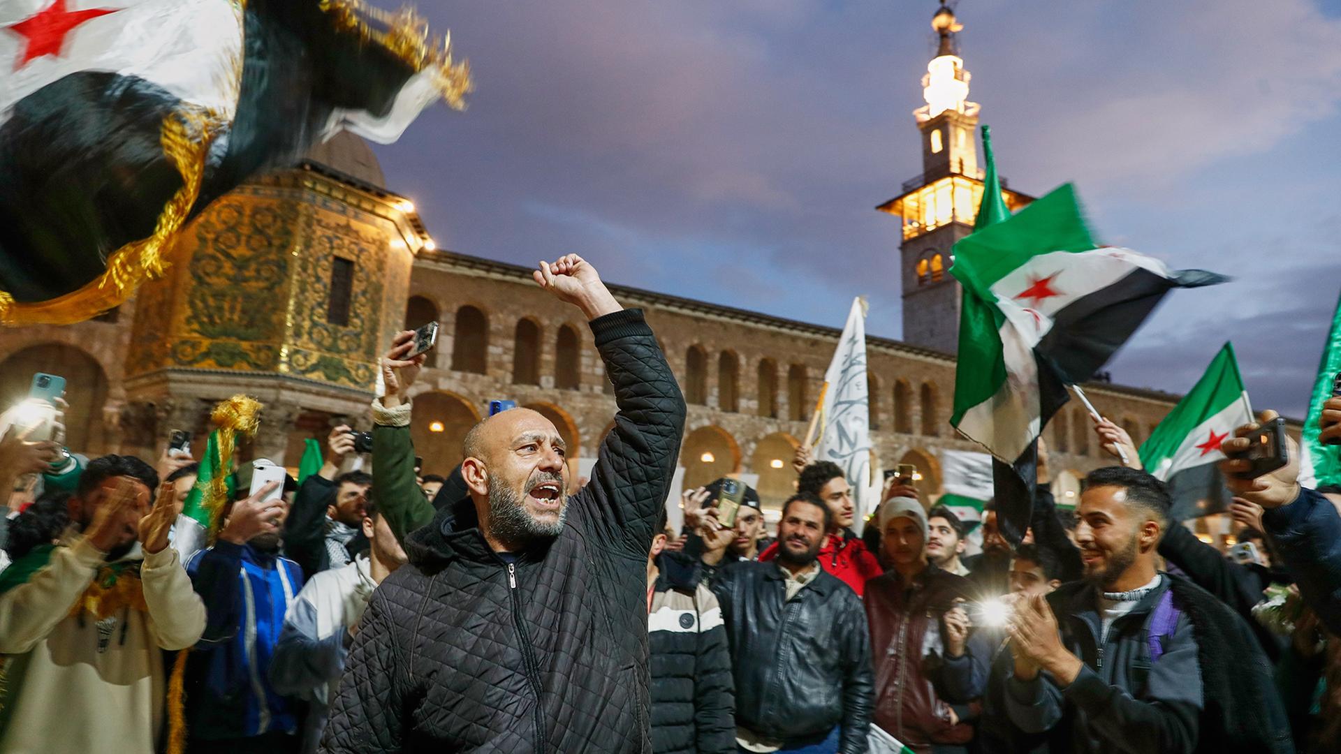 Syrer rufen Slogans und schwenken Fahnen im Vorfeld der Feierlichkeiten zum ersten Jahrestag des Sturzes des Regimes von Assad in Syrien. | dpa