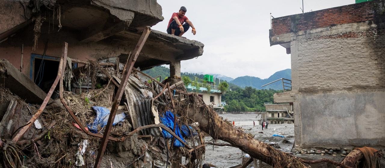 Menschen suchen in ihrem zerstörten Haus in Nepal nach Habseligkeiten.