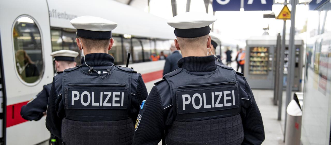 Zwei Bundespolizisten stehen am Gleis vor der Abfahrt eines ICE am Kieler Hauptbahnhof.