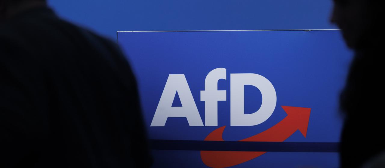 Die Silhouetten von zwei Personen vor dem AfD-Logo