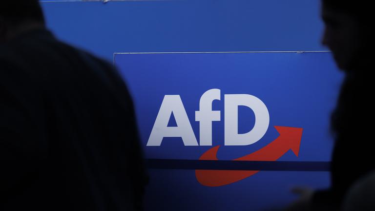 Die Silhouetten von zwei Personen vor dem AfD-Logo