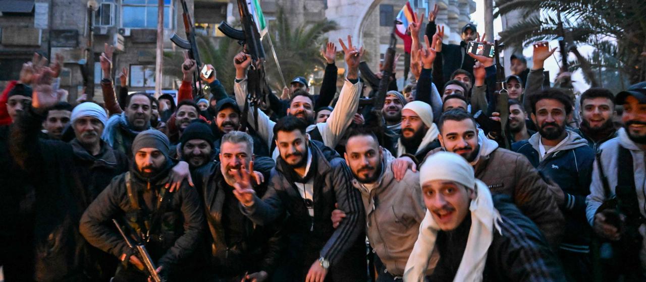 Syrer jubeln, als sie sich auf einer Straße im Damaszener Vorort Jaramana versammeln.