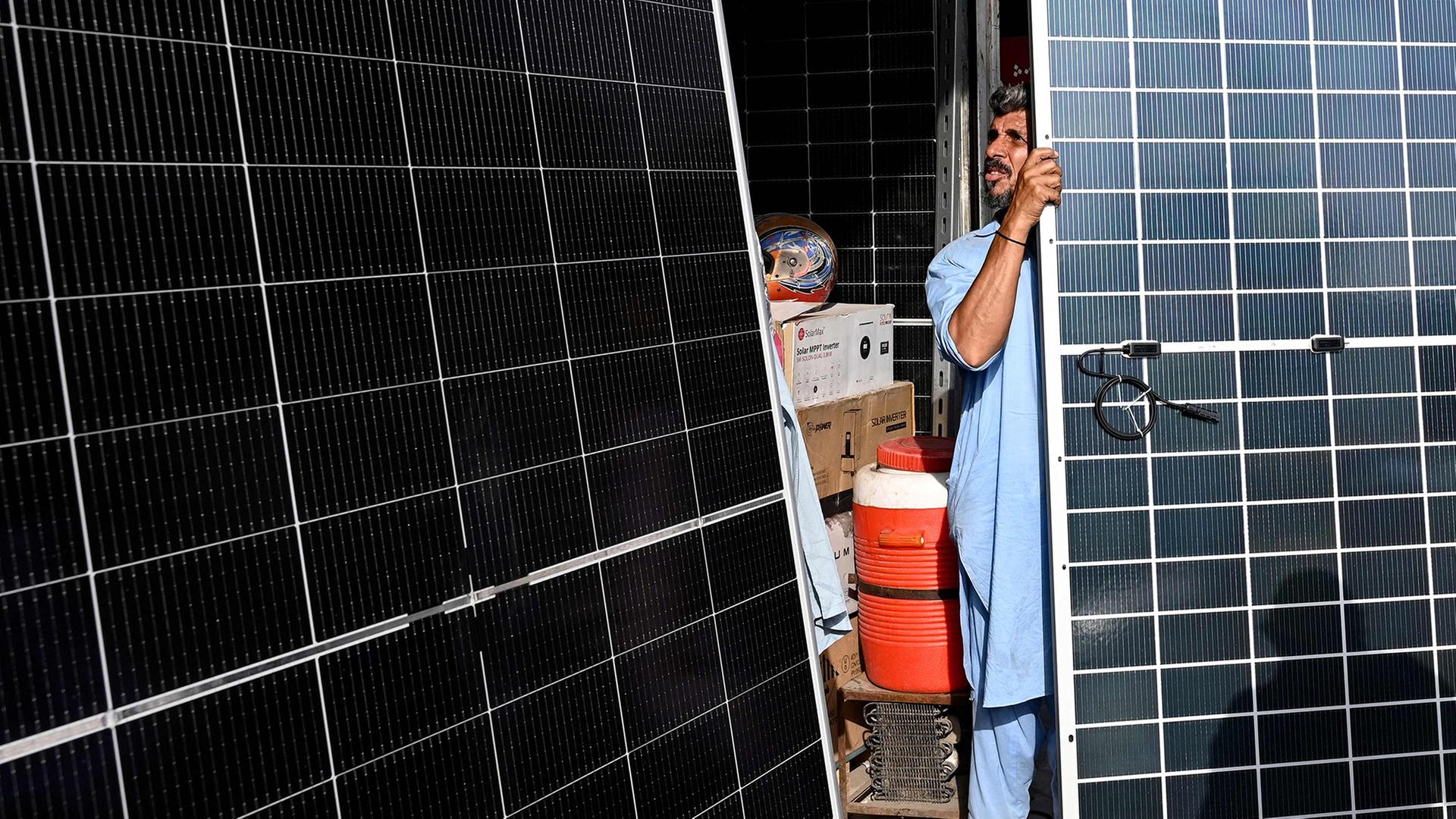 Ein Arbeiter trägt Solarzellen auf einem Markt in Lahore in Indien. | AFP