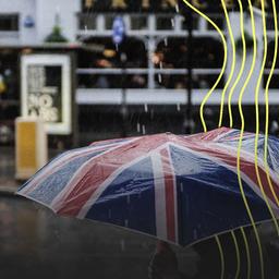 Eine Person geht mit einem Regenschirm mit Motiv britischer Flagge durch ein regnerisches London.