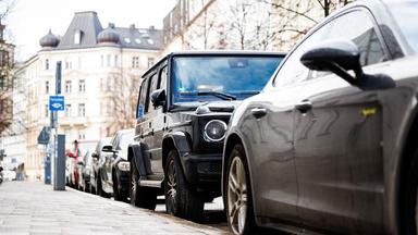 Ein SUV steht geparkt zwischen kleineren Fahrzeugen auf einem Parkstreifen.