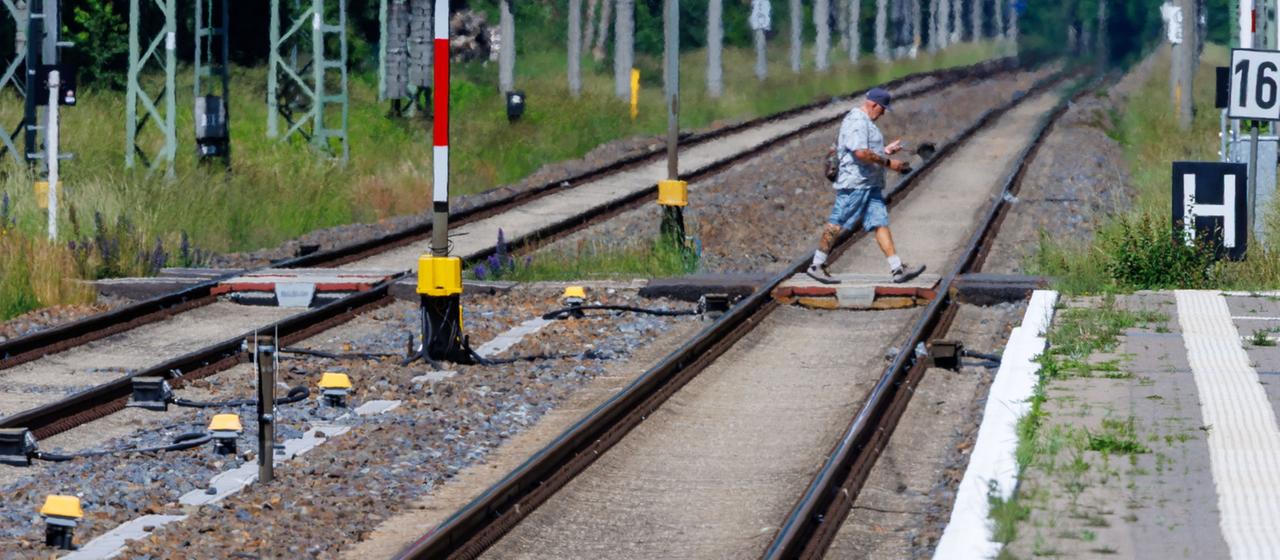 Ein Fußgänger geht über einen Bahnübergang auf der Strecke Berlin-Hamburg