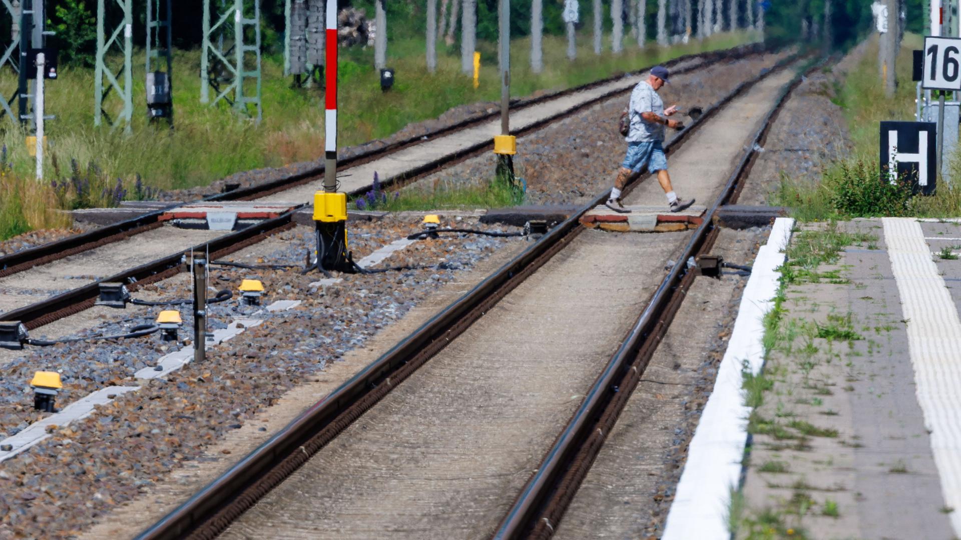 Ein Fußgänger geht über einen Bahnübergang auf der Strecke Berlin-Hamburg | Jens Büttner/dpa