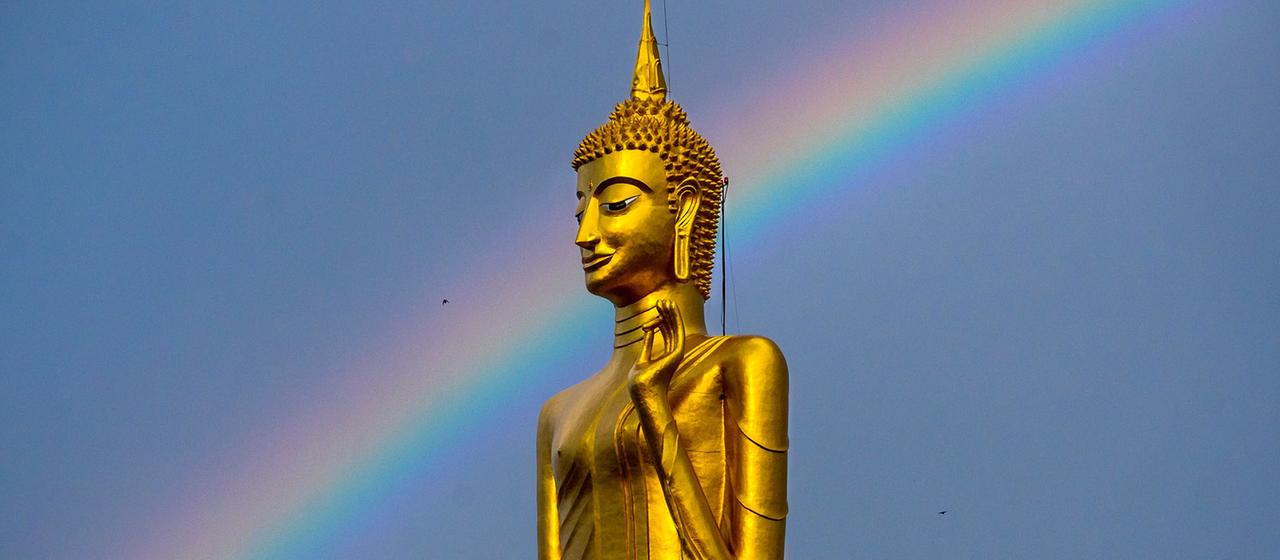 Ein Regenbogen ist hinter einer Buddha-Statue in Roi Et, Thailand, zu sehen.