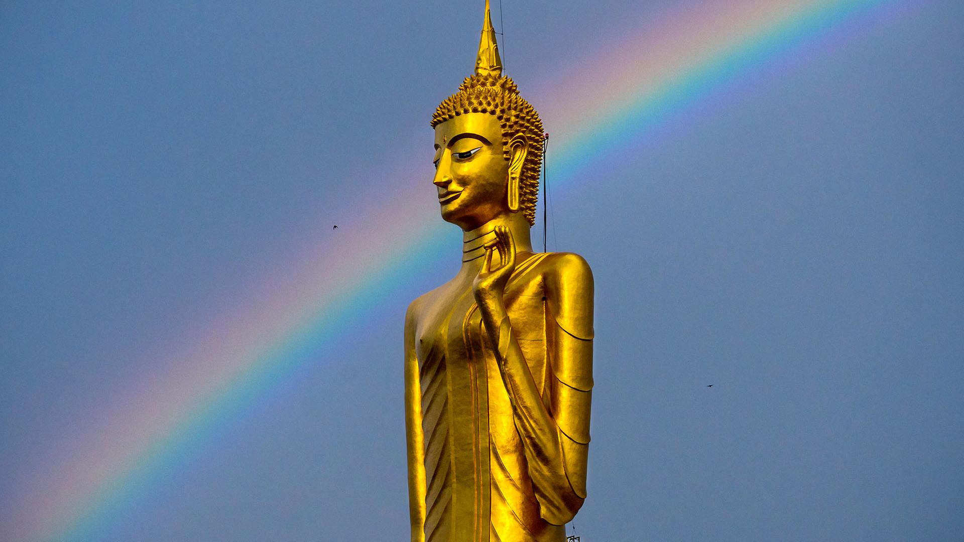 Ein Regenbogen ist hinter einer Buddha-Statue in Roi Et, Thailand, zu sehen. | picture alliance/dpa/ZUMA Press 
