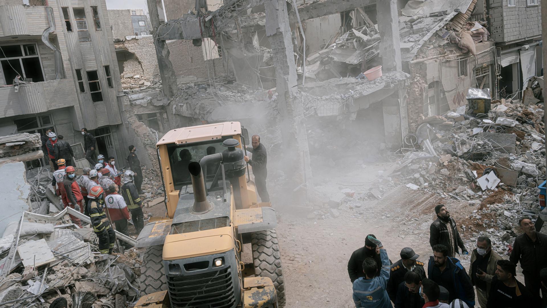 Rettungskräfte setzen im Nordwesten des Iran einen Bagger ein, um Trümmer zu beseitigen. | AP