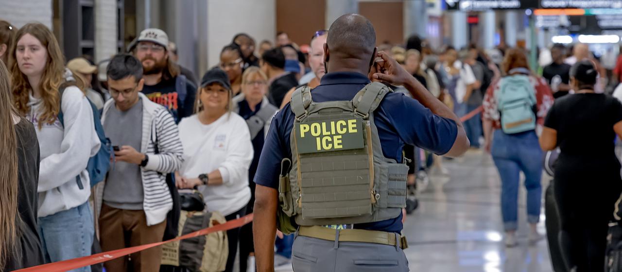 Ein ICE-Beamter geht an wartenden Passagieren am Flughafen Hartsfield-Jackson in Atlanta entlang.