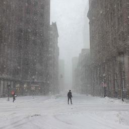 Menschen überqueren bei starkem Wind und heftigem Schneefall eine Straße in Boston (Massachusetts, USA).