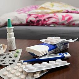 Medikamente und Taschentücher liegen auf einem Nachttisch