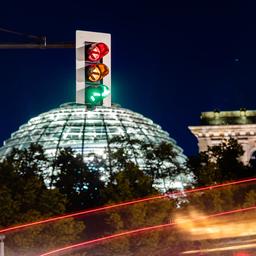 Eine Ampel vor dem Reichstagsgebäude leuchtet in einer Langzeitbelichtung in allen drei Phasen.