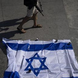 Ein israelischer Soldat, der nicht im Dienst ist, geht an Kerzen und der Nationalflagge Israels vorbei.