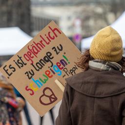 Zwei Frauen stehen mit einem Schild auf der Großdemonstration in Dresden.