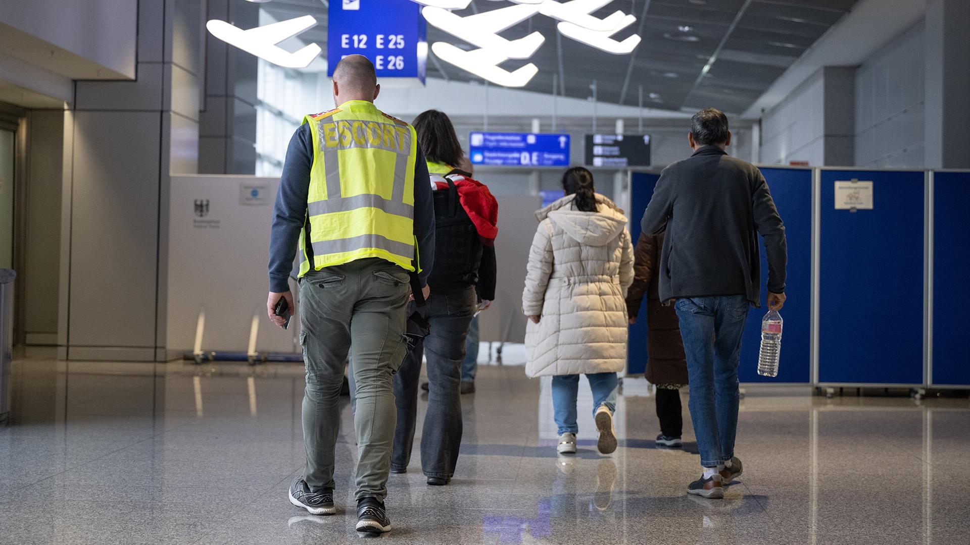Eine Familie wird von Beamten der Bundespolizei (l) zu einem Abschiebeflug nach Pakistan begleitet. | dpa