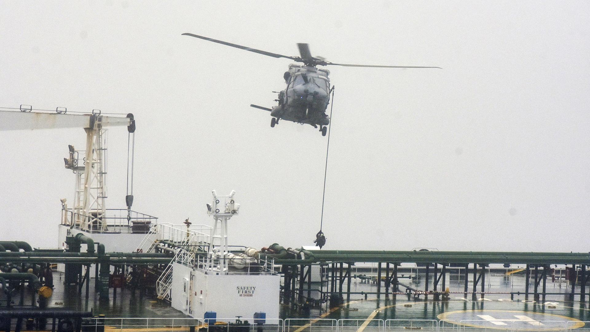 Menschen seilen sich von einem Militärhubschrauber auf ein Tankschiff ab. | Marine nationale française/AP/dpa