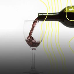 Rotwein wird in ein Glas gegossen, vor weißem Hintergrund.