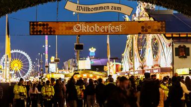 Sicherheitsbeamte stehen am Rande von Fahrgeschäften auf dem Oktoberfest.