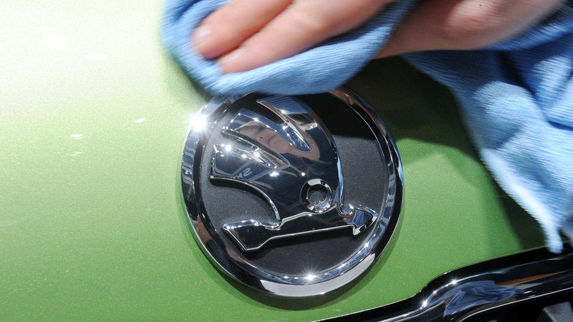 Ein Skoda-Logo an einem Auto wird poliert. | picture alliance / dpa