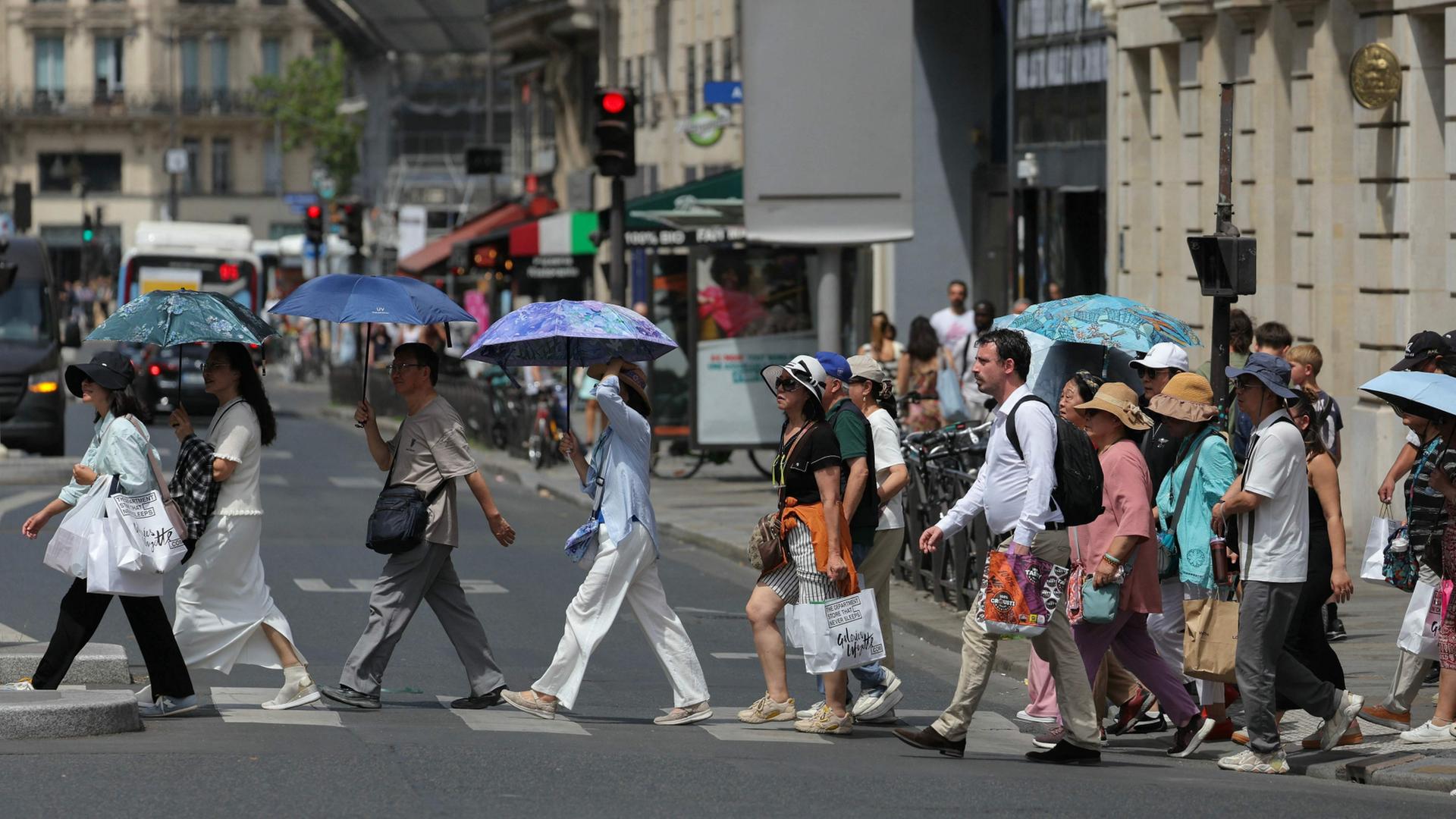 Menschen mit Schirmen �berqueren eine Stra�e in Paris | AFP