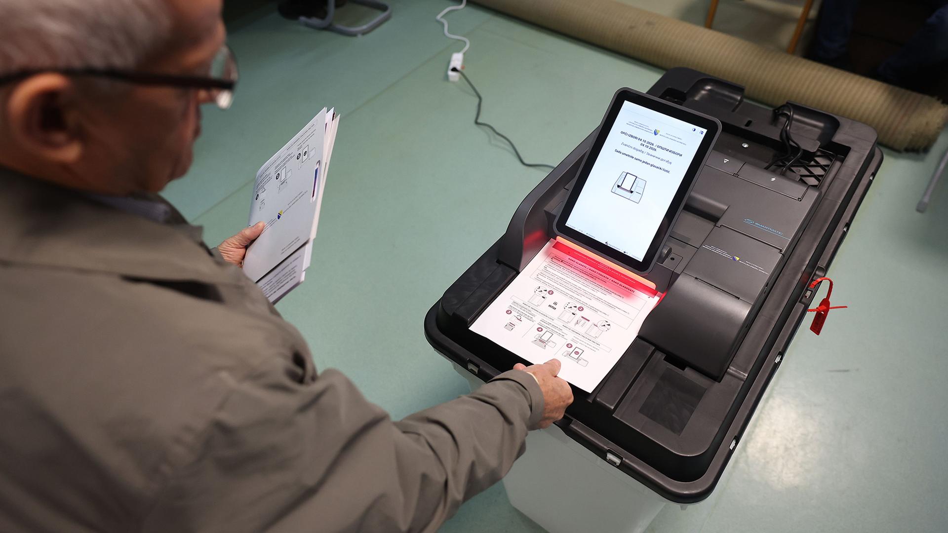 Ein Mann wirft seinen Stimmzettel in eine elektronische Wahlurne.  | Armin Durgut/AP/dpa