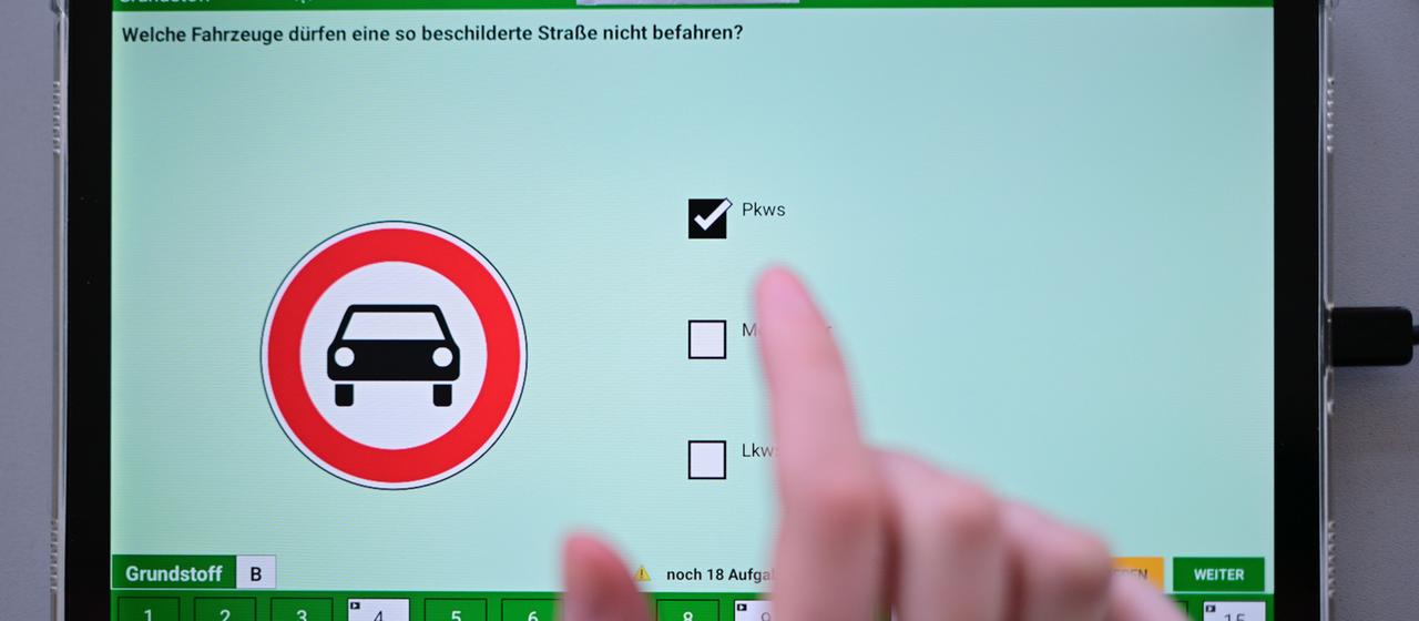 Eine Hand vor einem Bildschirm mit Führerschein-Lehrmaterial