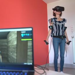 Eine Frau steht neben einem Laptop und trägt eine VR-Brille.