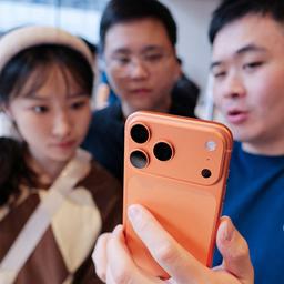 Personen schauen sich ein Smartphone in einem Elektronikgeschäft in China an.