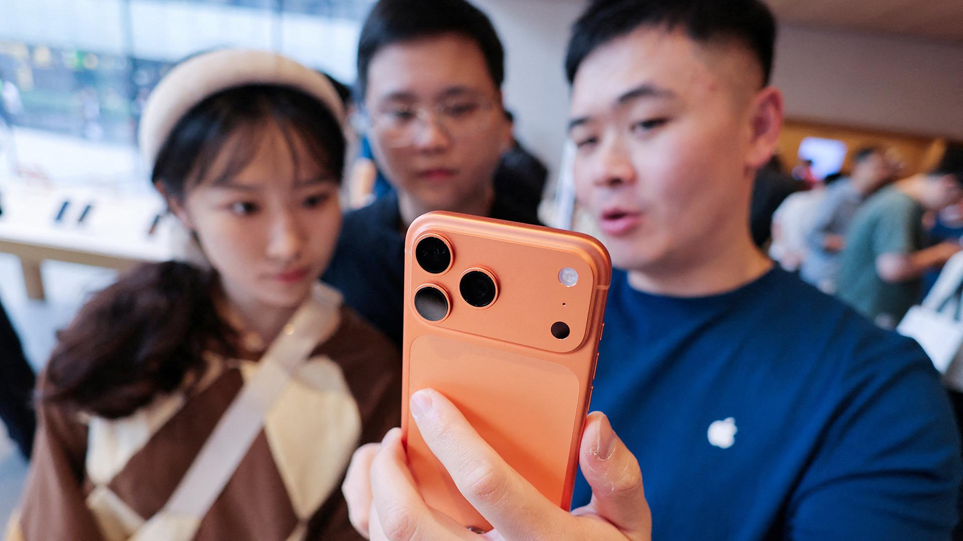 Personen schauen sich ein Smartphone in einem Elektronikgeschäft in China an. | REUTERS