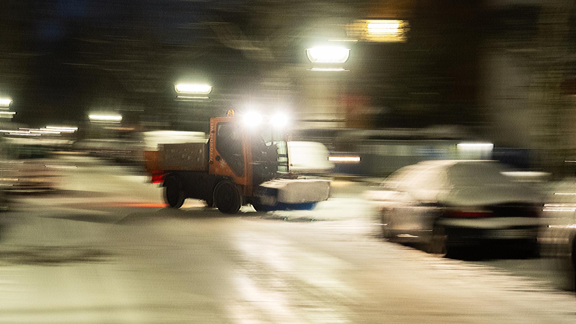 Ein Schneeräumfahrzeug fährt im nächtlichen Einsatz über einer Straße. | dpa