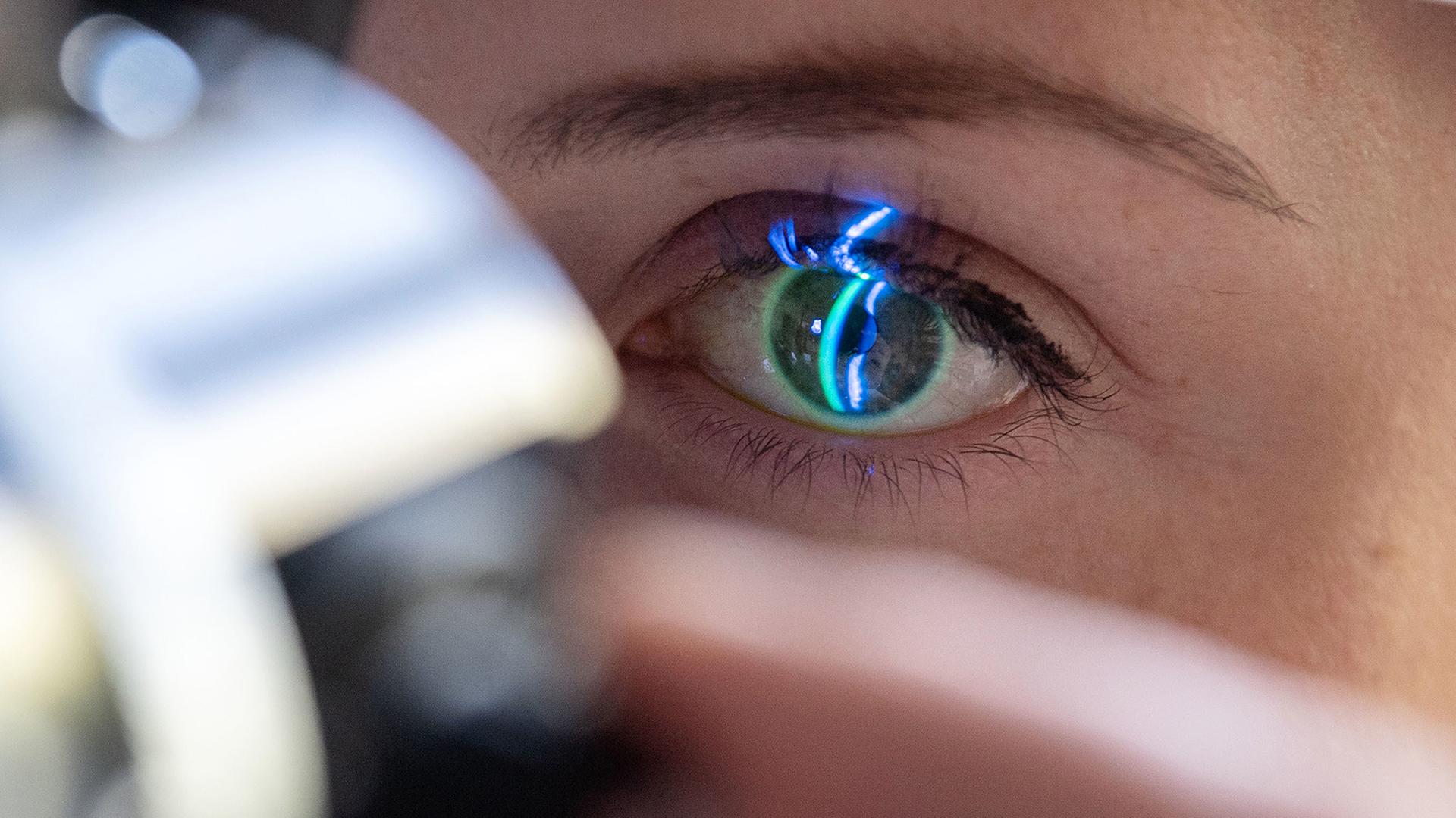 Ein Arzt untersucht das Auge einer Frau. | picture alliance/dpa