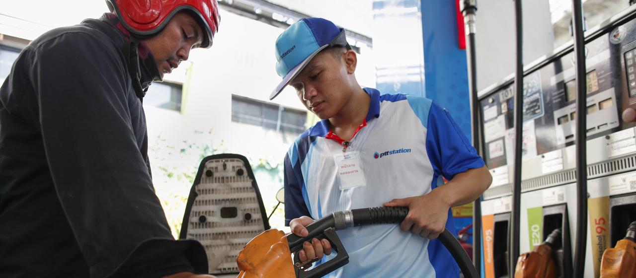 Ein Tankwart in Thailand betankt ein Moped.